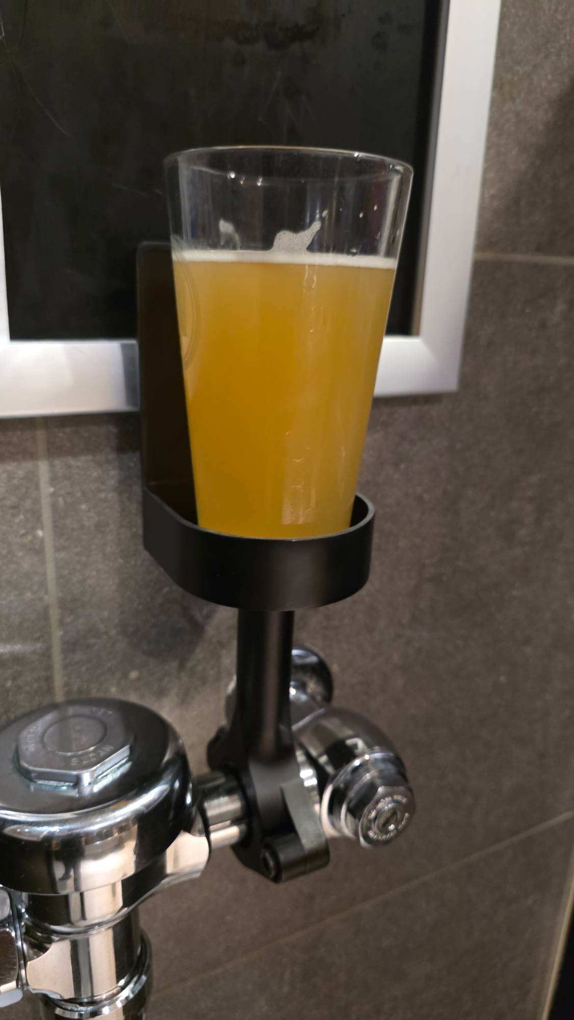 DrinkTight holding a beer on a urinal flush valve